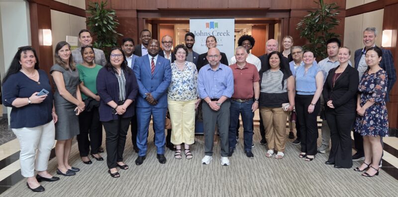 A group of people from different countries posing for a photo together at an AI delegation meeting hosted by the Johns Creek Chamber of Commerce in July 2026.