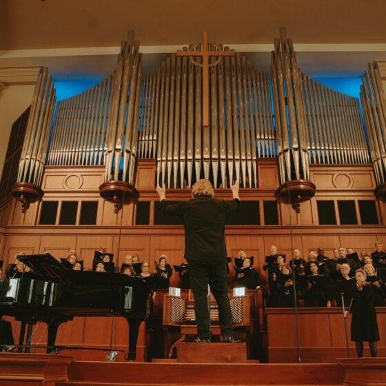 Wide view of the Johns Creek Chorale led by Dr. Nathan Frank, performing in front of an audience.
